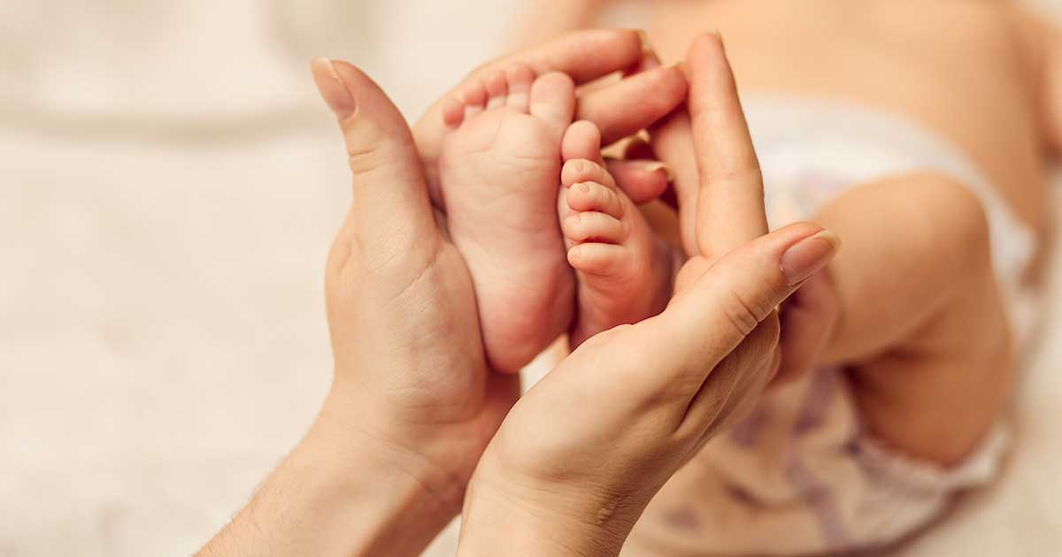 mani di donna su piedi neonato