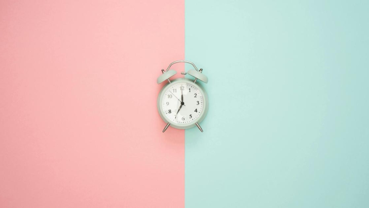 Orologio su uno sfondo azzurro e rosa.