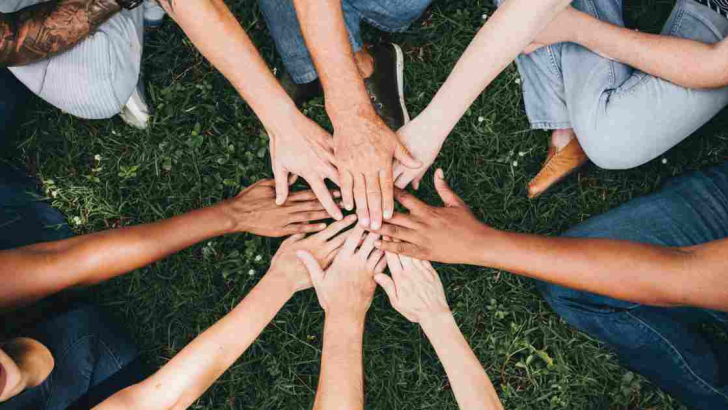 mani una sopra l'altra con braccia a stella