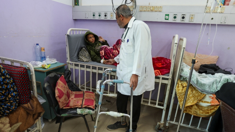 Il medico palestinese Khaled al-Saedni, la cui gamba è stata amputata dopo essere stata ferita in un attacco israeliano, controlla un bambino all'ospedale dei martiri di Al-Aqsa a Deir al-Balah, nella Striscia di Gaza centrale, l'8 gennaio 2025. REUTERS/Ramadan Abed